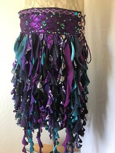 This one of a kind mermaid belt skirt is a unique wearable art piece that is made from reclaimed fabrics and comes with an adjustable pocket.  Wearing this garment will give you a nigh irresistible urge to spin around and shimmy and smile. The Purple Scales and Sequins belt has a base layer of sparkly purple scales and a top layer of lace adorned with iridescent sequins and beading and trimmed out with silver cording and gems the belt. It is a two piece belt that is fastened on the body with lacings on both hips for maximum flexibility in sizing.  It is lined with cotton fabric for comfort. This belt measures about 29 inches in length and is approximately 5.5 inches wide.  I recommend a hip size range of 31 to 43 inches. The belt comes with two removable pockets that hook on to grommets in Mermaid Belt, Sequins Belt, Witch Mermaid, Sequin Fringe Skirt, Mermaid Tail Skirt, Bellydance Costume, Crochet Slouch Hat, Belt Skirt, Tassel Skirt