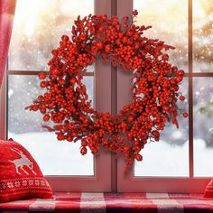 a red wreath sitting on top of a window sill in front of a snow covered window