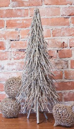 a christmas tree made out of branches on top of a wooden table next to two balls