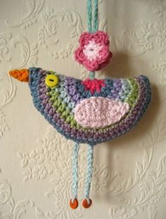 a crocheted bird ornament hanging on a wall