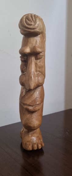 a wooden carving of a man's head on top of a wood table in front of a white wall