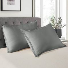 two gray pillows sitting on top of a bed