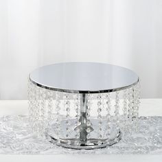 a round table with crystal beads on the top and silver metal base, in front of a white background