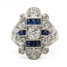 The Bella ring is an authentic vintage diamond ring from the Art Deco Era circa 1920. It centers 1 old mine cut diamond of I color and SI3 clarity that weighs 1.05ctw. Sixteen old mine cut diamonds of H color and VS2 clarity that weigh 0.90ctw and 10 natural calibrated French cut sapphires that weigh 1ctw are set throughout the setting of this ring. This ring is size 7 ½ and can be sized. Ring measurement: 22mm by 18mm by 5mm  Total weight: 6.8 grams/ 4.4dwt Heirloom Brilliant Cut Sapphire Ring Collectible, Heirloom Sapphire Ring With Brilliant Cut For Collectors, Antique Sapphire Ring With Single Cut Diamonds, Vintage Platinum Sapphire Ring With Diamond Cut, Vintage Sapphire Ring With Single Cut Diamonds, Heirloom Sapphire Ring With Rose Cut Diamonds In Platinum, Antique Sapphire Ring With Diamond Center Stone, Vintage Sapphire Ring With Single Cut Diamonds For Anniversary, Victorian Sapphire Ring With Diamonds For Anniversary