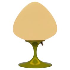 a green table lamp with a white shade on it's base and a light bulb in the shape of an egg