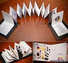 an open book on top of a wooden table next to some folded up books and papers