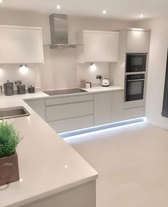 a kitchen with white counter tops and lights on the wall above the stove, sink and oven