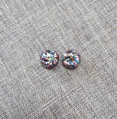 Rainbow glitter stud earrings in a round shape with your choice of posts! Super sparkly with a retro vibe. The earrings measure approx. 12mm in diameter. Resin with your choice of posts: 🔹 Standard metal posts: surgical steel, silver tone. 🔹 Titanium posts (with surgical steel backs): darker silver color. 🔹 Sterling silver posts & backings: .925 sterling silver 🔹 Plastic posts & backings: transparent plastic. 🔹 Clip on earrings: silver tone metal Stuff to know: - I do not guarantee Silver Glitter Round Earrings, Multicolor Round Clip-on Earrings, Glitter Round Earrings For Gifts, Multicolor Round Clip-on Earrings For Party, Kawaii Hair Clips, Rainbow Choker, Glitter Stud Earrings, Rainbow Confetti, Earrings Kawaii