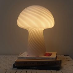 a mushroom lamp sitting on top of two books next to a white wall mounted light