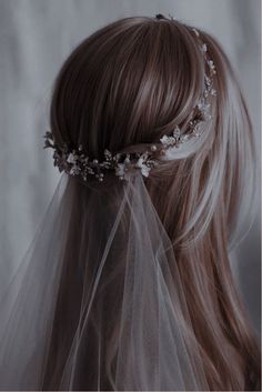 the back of a woman's head wearing a veil with flowers and leaves on it