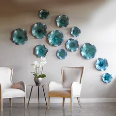 two chairs and a table in front of a wall with blue flowers on the plates