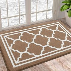 a brown and white door mat sitting on top of a wooden floor next to a potted plant