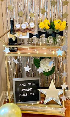 the bar cart for the oscars is decorated with gold and white stars, champagne bottles, and flowers