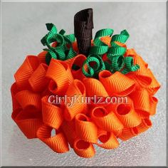 an orange and green hair bow on top of a wooden stick in the shape of a pumpkin