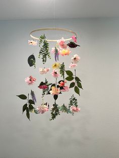 a mobile with flowers hanging from it's sides in a room next to a wall