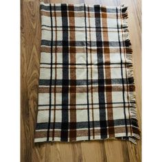 a brown and white plaid blanket laying on top of a wooden floor