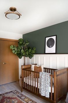 a baby crib with a potted plant in the corner and pictures on the wall above it