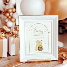 a white frame with a winnie the pooh print on it next to presents and balloons