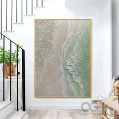 a painting hanging on the wall next to a stair case in a room with white walls and wooden floors