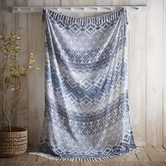 a blue and white curtain hanging on a wooden wall next to a potted plant