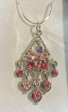 This is a stunning and unique necklace. The pendant is repurposed from a vintage earring. Absolutely lovely as a necklace, with 13 stunning Rhinestones. The Rhinestones very in colors of pink and crystal. Very elegant. Elegant Pink Rhinestone Necklace Gift, Elegant Pink Rhinestone Necklace For Gift, Pink Jewel Pendant Jewelry, Pink Jeweled Pendant Jewelry, Pink Pendant Necklace With Jewels, Pink Round Pendant Jewelry With Lobster Clasp, Rhinestone Dangle Necklaces As Gifts, Rhinestone Dangle Necklaces For Gifts, Vintage Pink Jeweled Necklace