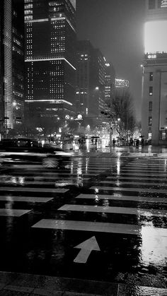 a city street at night with buildings and an arrow painted on the wet pavement in black and white