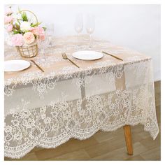 the table is set with two plates and wine glasses on it, next to a basket of flowers