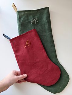 someone is holding two christmas stockings with the letters f and n on them, one in green and one in red