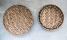 two brown woven bowls sitting on top of a cement floor next to eachother