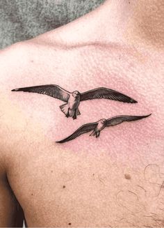 a man's chest with two seagulls flying in the sky on it