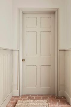 an empty room with a white door and red brick flooring in front of it