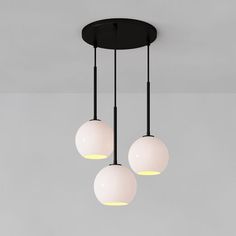 three light fixtures hanging from a ceiling in a room with grey walls and flooring