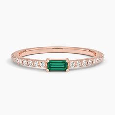 a rose gold ring with an emerald and diamonds