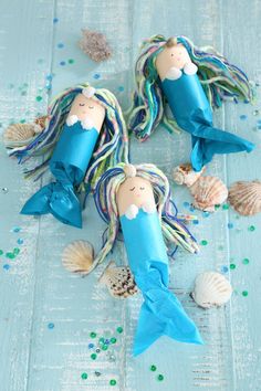 two little mermaids made out of paper and some sea shells