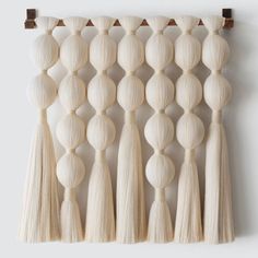 a wall hanging made out of wood with tassels on the top and bottom