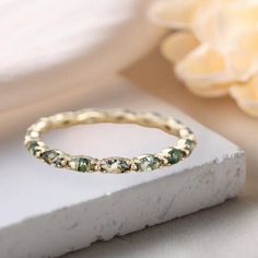 a close up of a ring on a white surface with a flower in the background