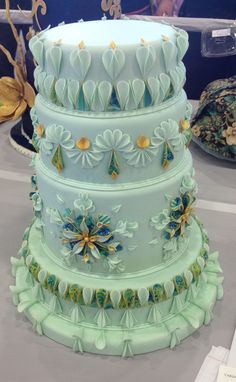 a three tiered cake is on display at a wedding or party event in blue and green