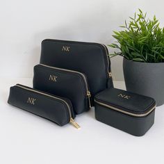 three black cosmetic bags sitting next to a potted plant