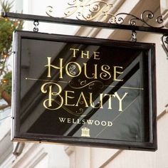 a sign hanging from the side of a building that says the house of beauty wellswood