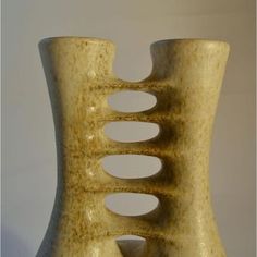 a vase that is made out of wood and has holes in the top half of it