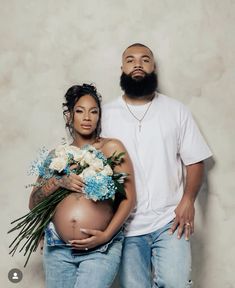 a man and woman standing next to each other with flowers on their stomachs,