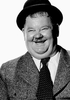 a black and white photo of a man in a suit with a hat on his head