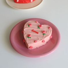 a heart shaped cake sitting on top of a pink plate next to a white plate