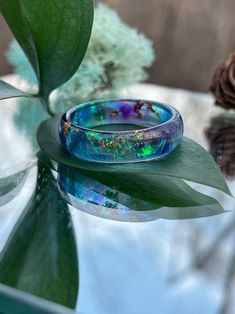 a blue ring sitting on top of a table next to a green leafy plant