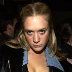 a woman with blonde hair and blue eyes is looking at the camera while wearing a black leather jacket