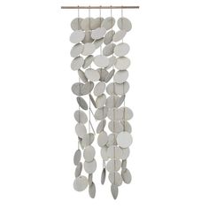 a wind chime with white discs hanging from it's wooden rod and string