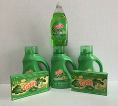 three bottles of gain liquid next to each other on a white surface with green packaging