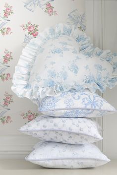 four pillows stacked on top of each other in front of a wallpapered background