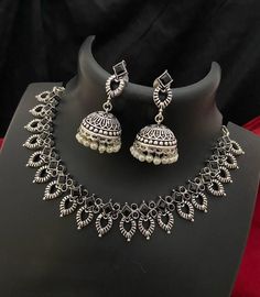 This stunning oxidized silver necklace set, adorned with vibrant color stones and paired with exquisite pearl Jhumka earrings, is a beautiful example of traditional Indian tribal jewelry. The intricate design showcases a perfect blend of ethnic charm and modern elegance, making it ideal for weddings, festivals, and special occasions. The necklace features a detailed pattern withCZ color stone accents, while the Jhumka earrings are crafted with a classic dome design and finished with delicate pearl drops. This set adds a unique and stylish touch to any traditional or contemporary outfit, making it a must-have for your jewelry collection. Features: Antique oxidized silver finish for a vintage look CZ color stones with intricate detailing Matching Jhumka earrings with pearl drops Ideal for br Oxidised Jewellery Necklaces, Antique Silver Jewelry Indian, Oxidized Choker, Stylish Jewelry Accessories, Junk Jewellery, Oxidized Silver Necklace, Antique Silver Necklace, American Diamond Necklaces, Antique Silver Jewelry