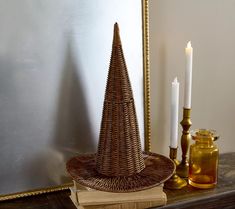 a wicker christmas tree sitting on top of a wooden table next to a candle